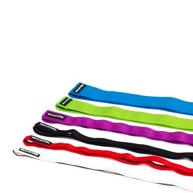 Five 41" Fabric Non-Slip Resistance Bands by Bells of Steel, in blue, green, purple, black, red, and white with "BELLS OF STEEL" labels are arranged on a white surface—ideal for powerlifting or mobility workouts.
