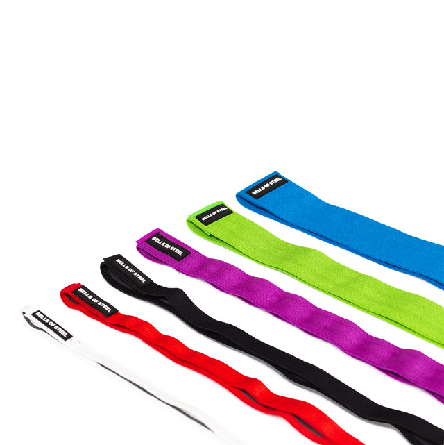 Five 41" Fabric Non-Slip Resistance Bands by Bells of Steel in white, red, black, green, and blue are arranged diagonally on a white surface. Each band features a black label with "BULLS & BUTTER" text; perfect for mobility or powerlifting.
