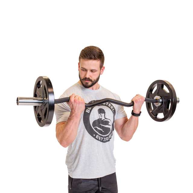 A bearded man performs a bicep curl with the Bells of Steel EZ Curl Bar (45"), displaying arm strength in a light gray T-shirt and black shorts against a plain white background.