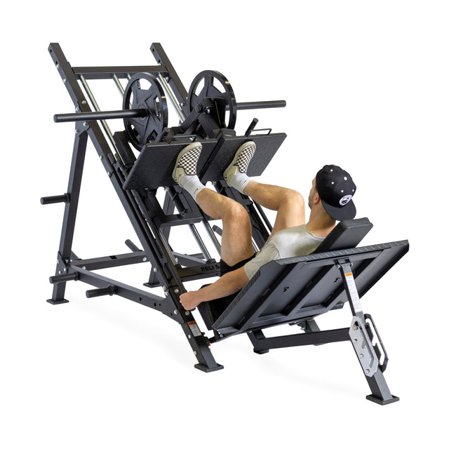 A person uses the Bells of Steel 2-in-1 Iso Leg Press & Hack Squat Machine (The Juggernaut), pushing weight plates with both feet while seated on the padded backrest.