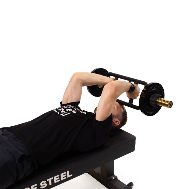 A person uses the Bells of Steel Tricep Bar to perform a tricep extension on a workout bench, arms bent and weights above their chest, against a white background.