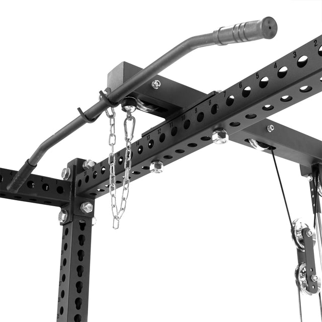 Close-up of a sleek black gym power rack from Bells of Steel, featuring a pull-up bar, chains, numbered bolt holes and the "Lat Pulldown & Low Row Rack Attachment - Hydra & Manticore" with an advanced pulley system and metal accents on a plain white background.