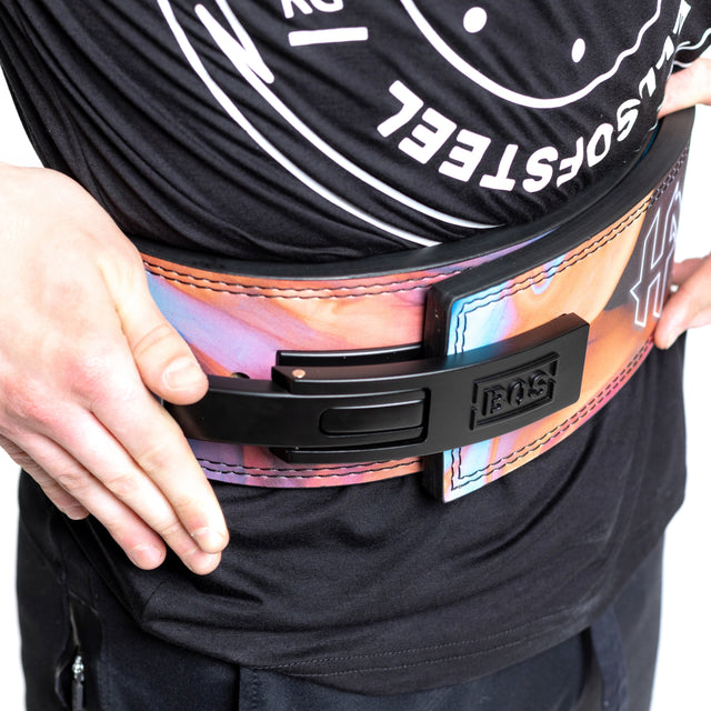 A person in a black shirt and pants holds the sides of a colorful Bells of Steel Lever Belt, featuring a black lever clasp.