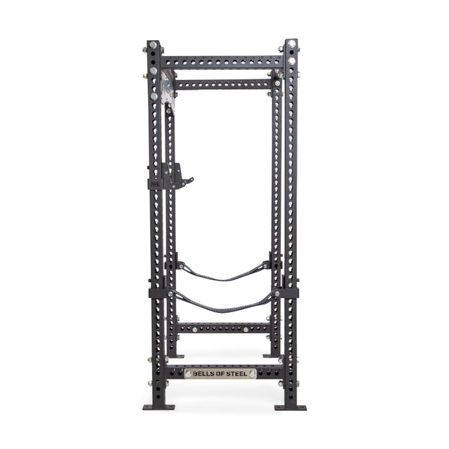 The Bells of Steel Manticore Four Post Power Rack - Prebuilt (3" x 3", 1" Holes) features multiple adjustment holes, safety straps, a pull-up bar, and sturdy black uprights—ideal for weightlifting and strength training at home.