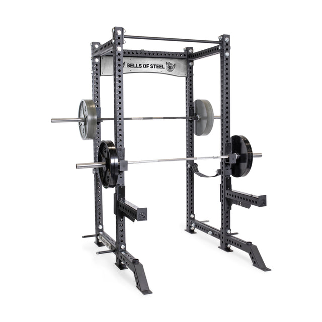 The Bells of Steel Manticore Four Post Power Rack Builder (3" x 3", 1" holes) includes adjustable safety bars and is perfect for strength training in your home gym with a loaded barbell and weight plates.