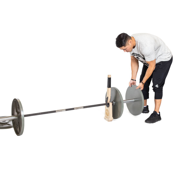 Using the Bells of Steel Meat Hook Deadlift Jack, a person easily lifts one end of a barbell set on the floor to load a weight plate.