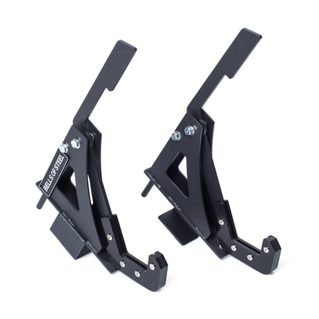 Two black Monolift Rack Attachments by Bells of Steel, featuring angled arms and bolts for secure bar adjustments and space-saving storage, stand side by side on a white background. One displays the “DEALS ON STEEL” label.