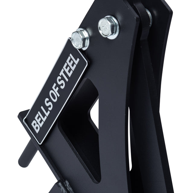 Close-up of the black metal Monolift Rack Attachment by Bells of Steel, showing bolts and branded label. Its space-saving design allows for easy bar adjustments or adding to your rack setup.