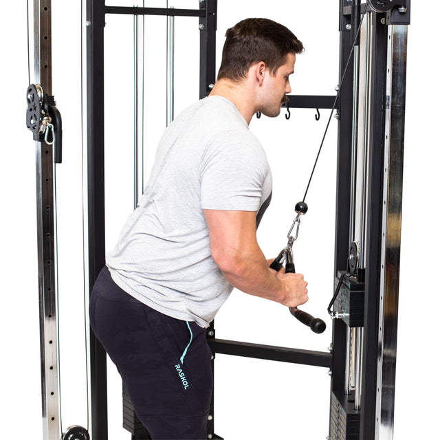 A man in a gray t-shirt and black shorts uses the Bells of Steel MULTI-PURPOSE V STYLE BAR for tricep pushdowns, gripping the handle with both hands and extending his arms downward to build muscle.