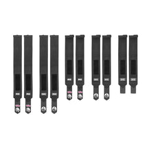 Nine Bells of Steel Mighty Wrist Wraps, made of black nylon with Velcro fasteners and branded labels, are lined up on a white background. These wraps offer wrist support and style—perfect for powerlifting essentials.