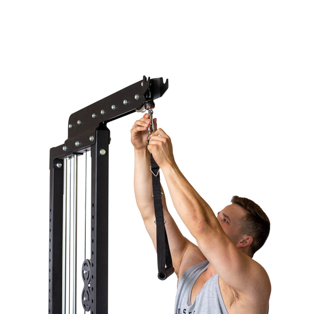 A man in a sleeveless shirt attaches the Bells of Steel Nylon Adjustable Length Single Handle Cable Attachment to a cable machine, getting ready for a workout. The background is plain white and uncluttered.