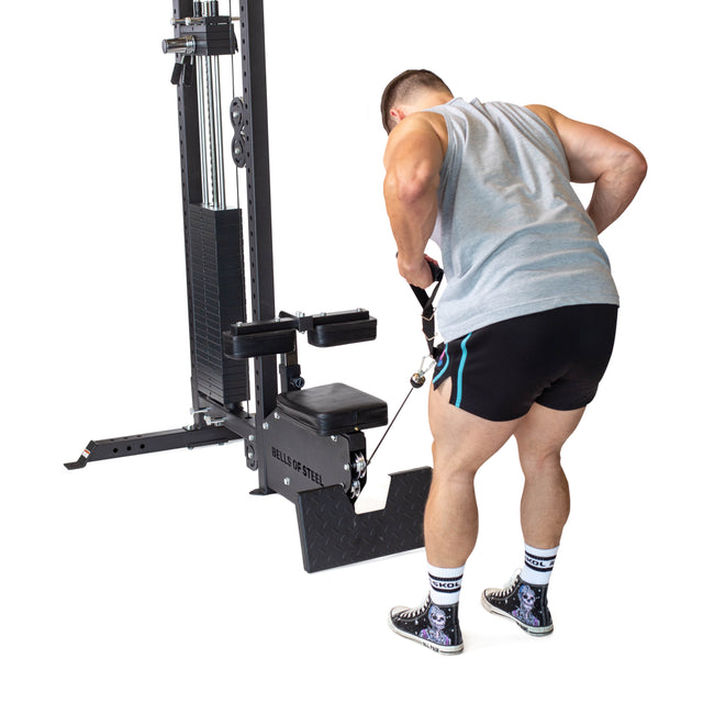 A man in a gray tank top and black shorts uses the Bells of Steel Nylon Adjustable Length Single Handle Cable Attachment to perform a cable row on a seated row machine; background is white.
