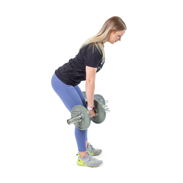 A woman uses the Bells of Steel Loadable Dumbbell Handle to perform a deadlift, bending at the hips with a straight back. She wears a black t-shirt, blue leggings, and gray sneakers, posing against a white background.