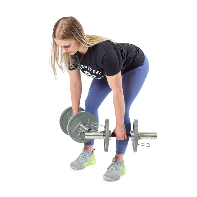A woman performs a bent-over exercise with Bells of Steel Loadable Dumbbell Handles in each hand, wearing a black T-shirt, blue leggings, and gray sneakers—a great move to enhance any home gym routine.