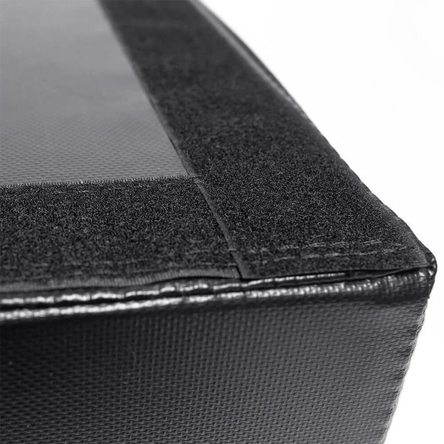 Close-up of a black textured corner with a Velcro strip and stitching, part of Bells of Steel Deadlift Pads (Pair) designed for weightlifting noise reduction, shown on a white background.