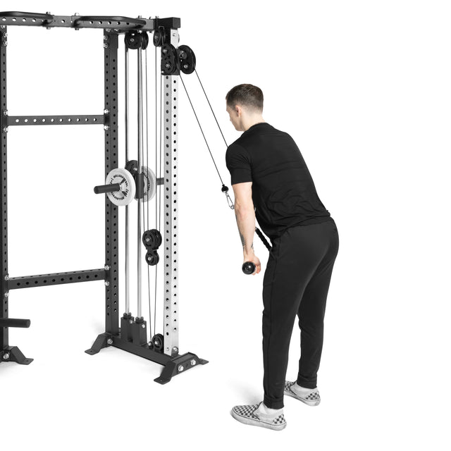 Wearing black workout clothes, someone skillfully uses the Bells of Steel Functional Trainer Cable Tower to perform a tricep pushdown. They stand with feet shoulder-width apart and slightly bent knees, pulling down the straight bar with efficiency.