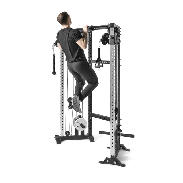 A person is performing a pull-up on the Bells of Steel Functional Trainer Cable Tower, clad in sleek black pants and shirt. This station includes cable towers and attachments, providing versatile workout options.