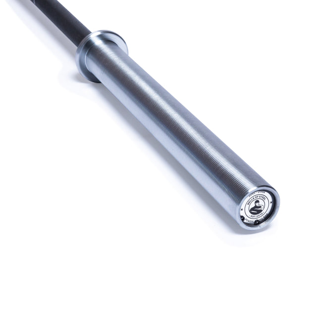 A close-up of the Bells of Steel Powerlifting Bar shows its silver sleeve with ribbed texture and logo, plus a black shaft—ideal as a budget power bar—isolated on a white background.
