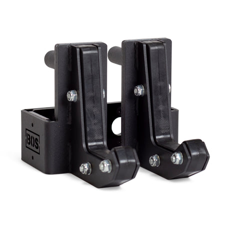 Two black metal Sandwich J-Cups by Bells of Steel with bolts and a rectangular base, designed as heavy-duty squat rack attachments. The BOS logo appears on the side of one holder.
