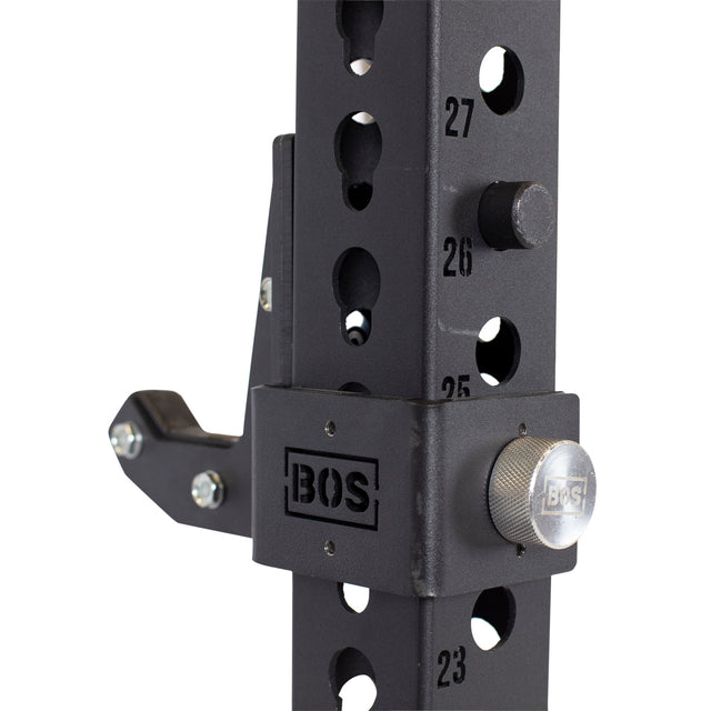 Close-up of a black squat rack upright with numbered adjustment holes, metal pin, Bells of Steel logo, and heavy-duty Sandwich J-Cups attachments on the side.