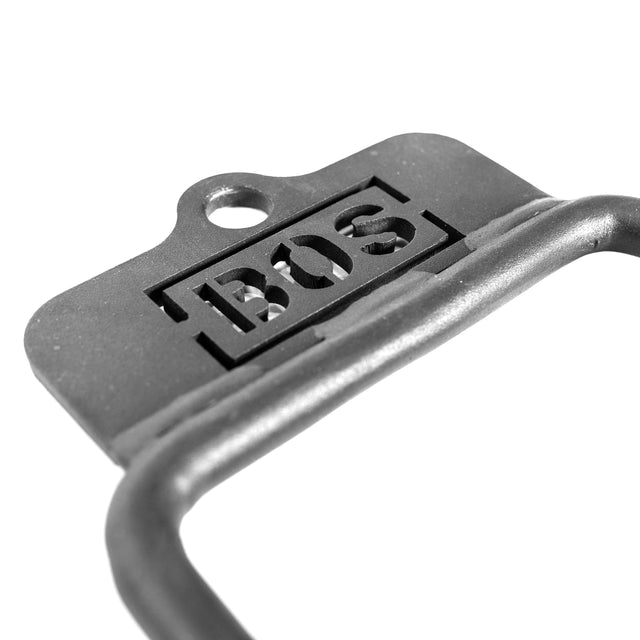 Close-up of the Bells of Steel Fat Bar - Single D Handle in black and white, showing "BOS" cut-outs, a hanging hole, and a curved grip strength bar in the foreground.