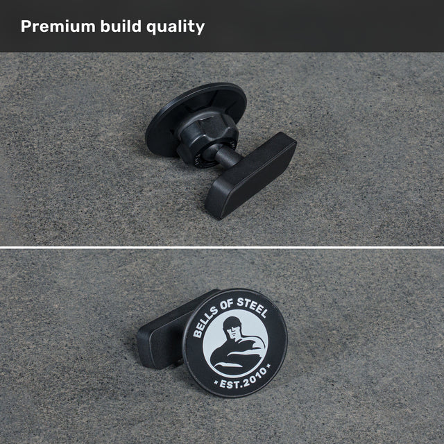 Two close-up views of the black knob on a gray surface highlight the “BELLS OF STEEL EST. 2010” stamp with a muscular figure logo and “Premium build quality” above—designed for perfect compatibility with the Bells of Steel USA Selfie Sentinel - Magnetic Rack Phone Holder, making it easy to capture hands-free workout videos or photos using your gym tripod.