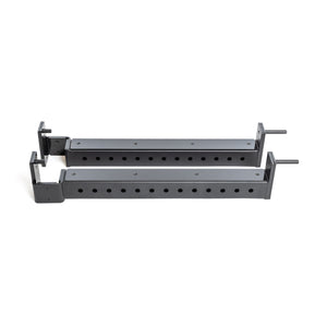 Two black metal Flip-Down Safeties by Bells of Steel, featuring multiple holes for height adjustment, are positioned parallel on a white background, ensuring training safety when used with a power rack.