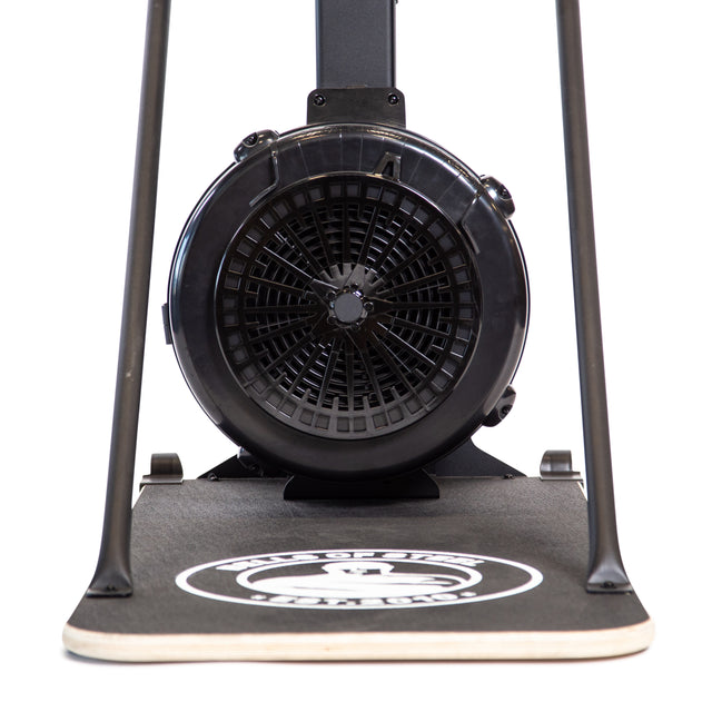 Close-up of the Bells of Steel Blitz Ski Trainer's black fan and flywheel on a textured base with a white circular logo, emphasizing the front design made for intense full-body workouts.