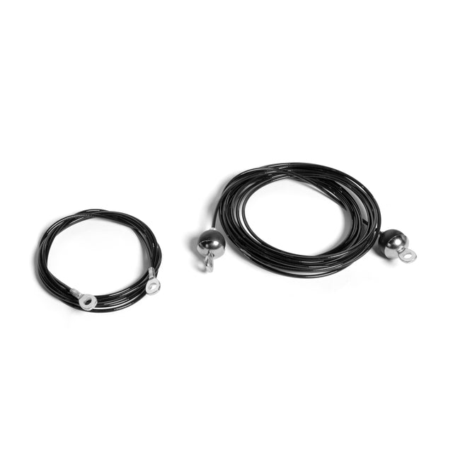 Two coiled black cable replacement wires lie on a white surface. The smaller coil is on the left, while the larger one is on the right. Each nylon cord designed for a Plate-Loaded Cable Tower by Bells of Steel USA features metal loops at both ends.