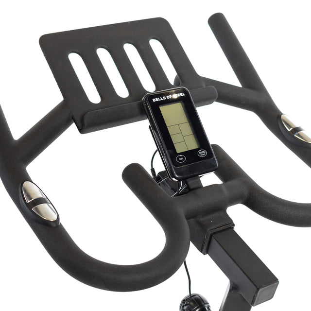 Close-up of the Blitz Indoor Cycling Bike's adjustable handlebars by Bells of Steel, featuring a digital monitor showing metrics. The grips include metallic sensors for precise feedback, with the brand name displayed on the monitor.