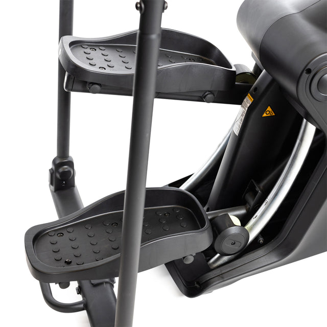 Close-up of the foot pedals and frame on the Bells of Steel Blitz Stepper shows textured grips and metal bars, making this black elliptical ideal for low-impact cardio workouts.