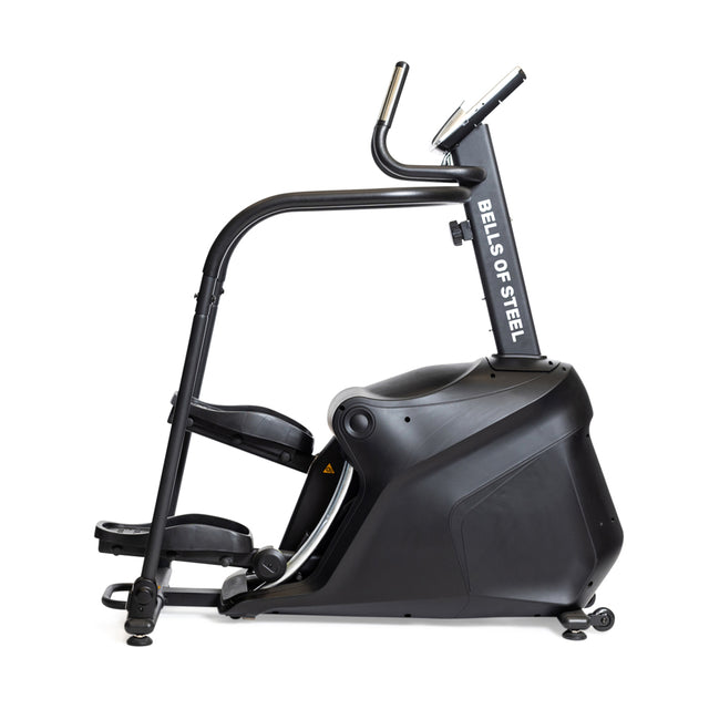 Side view of the Bells of Steel Blitz Stepper, a black indoor exercise machine with foot pedals, handlebars, and a digital display for low-impact cardio or stair climber workouts.
