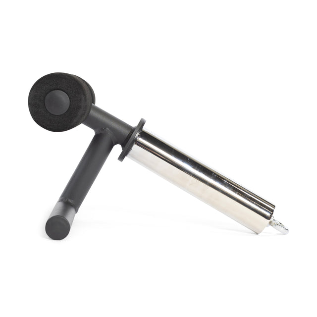 The Bells of Steel Tibialis Trainer Bar is a stainless steel and black handheld kitchen tool with a cylindrical body, angled handle, and a round black disc attachment on top, resembling an Olympic weight plate, shown on a white background.