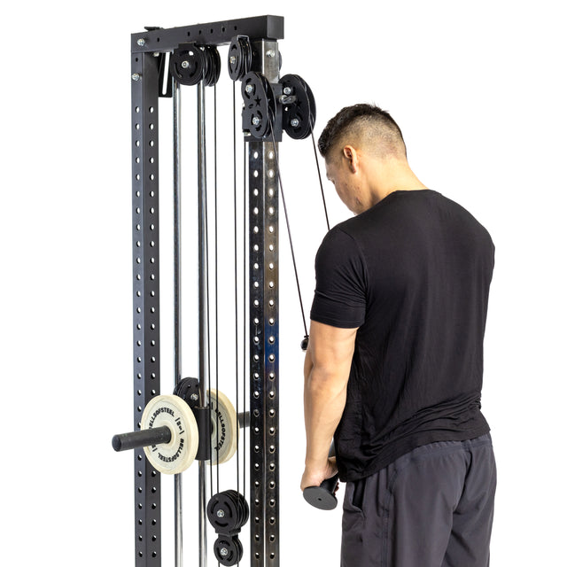 A man in a black shirt and shorts uses the Bells of Steel Fat Bar - Tricep Pressdown, gripping the handle with both hands and facing the cable machine to build grip strength.