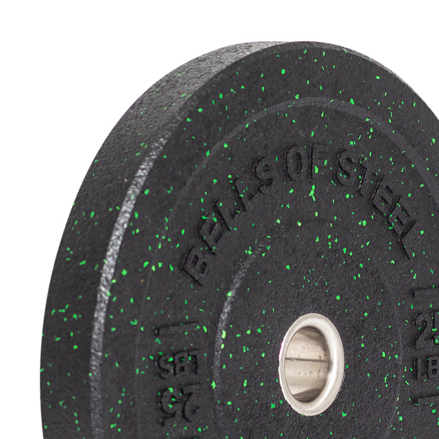 A close-up of a Bells of Steel Crumb Bumper Plate features a black plate with green speckles and "BELLS OF STEEL" etched on it. It has a central metal ring for easy barbell attachment.