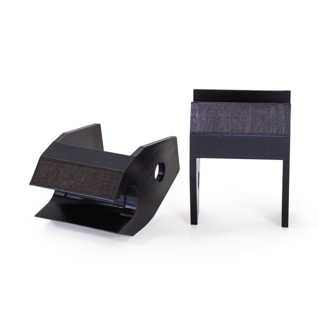 Two black, angular plastic Above Rack Barbell Holders by Bells of Steel are shown against a white background: one lies at an angle displaying a side hole, while the other stands upright on two legs.