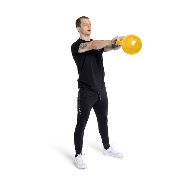 In a black t-shirt, black pants, and white sneakers, a person skillfully trains with a yellow Adjustable Competition Kettlebell by Bells of Steel against a white backdrop, showcasing strength and precision.