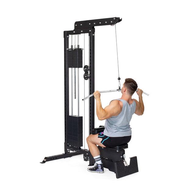 A man in a gray tank top and shorts uses the Bells of Steel Lat Pulldown Bar, seated on a bench and pulling the bar toward his chest to work his back muscles.
