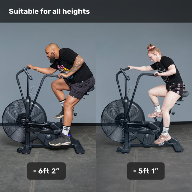 Two people, one 6'2" and the other 5'1", ride the Bells of Steel Blitz Air Bike together, showing its belt drive design easily fits users of all heights—making it a perfect addition to any home gym.