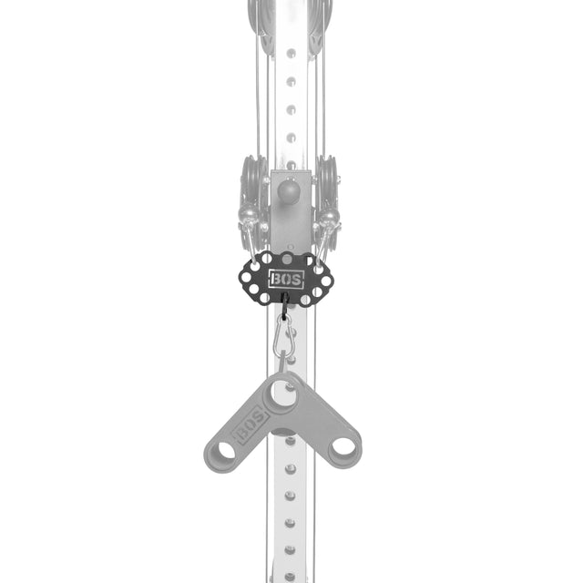 A black Bells of Steel USA Kaizen Multi-Link pulley system is mounted on a vertical metal bar with multiple holes; two gray levers hang in a Y-shape from the cable connector. The grayscale image highlights the black pulley.
