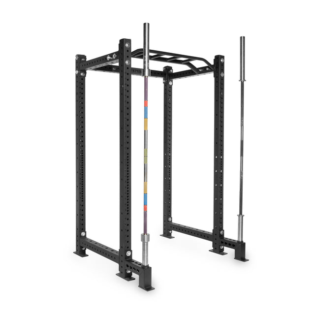A black Bells of Steel power rack with multiple adjustment holes, Front Foot Stabilizers, and a pull-up bar is shown. Two barbells, one featuring colorful markings, are stored vertically against the rack for easy access.