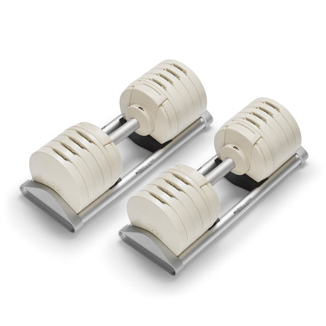 A pair of Bells of Steel USA NÜOBELL-S Adjustable Dumbbells with a sleek, modern design and metallic handles on silver stands—featuring multiple weight plates, they're ideal for any home gym.