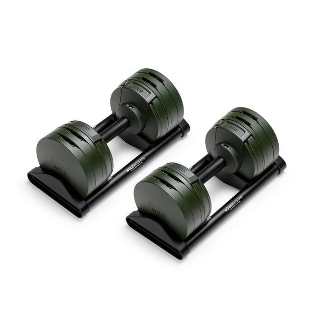 A pair of Bells of Steel USA NÜOBELL-S Adjustable Dumbbells with round, dark green plates sit on black trays, perfect for any home gym and shown against a white background.