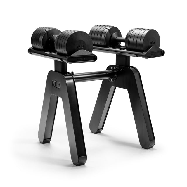A pair of NÜOBELL-S adjustable dumbbells sits on a sleek, black NÜOBELL-S Floor Stand by Bells of Steel USA, with "NUO" branding displayed, all set against a plain white background.
