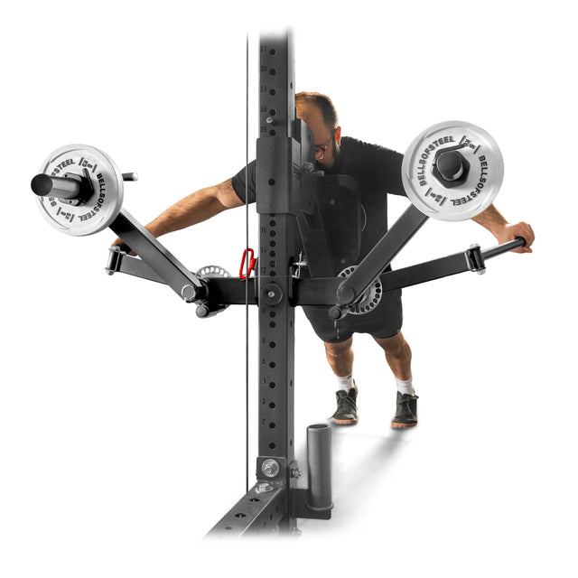 A man wears workout clothes and glasses while using the Bells of Steel Shoulder Boulder/Chest Fly Attachment, pushing angled arms on a vertical rack for a shoulder workout with this space-saving gym equipment.