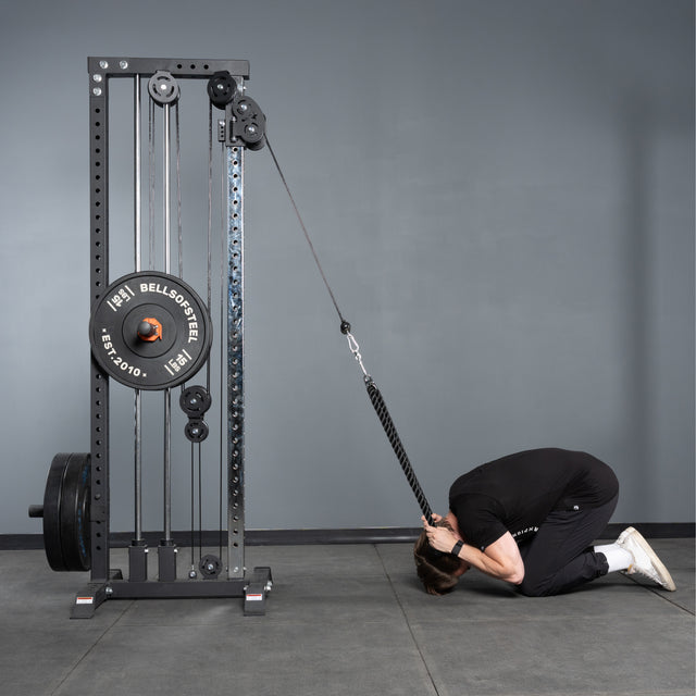 A person kneels, using the Bells of Steel Extra Long Tricep Rope Extension (137cm) attached to a weight machine to perform cable crunches, facing downward with their forehead close to the floor.