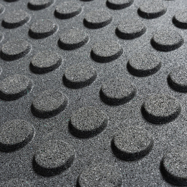 Close-up of Bells of Steel Rubber Flooring Gym Mat 24" x 24" shows its textured black surface with evenly spaced, raised circular bumps for enhanced grip and safety—ideal for heavy-duty gym environments.