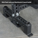 Close-up of the base of a black metal Manticore Two Post Converter Bench by Bells of Steel USA, with mini feet secured by bolts on concrete. Top text: “Mini feet only on Manticore 2 post build.” Premium gym equipment for your space.