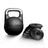 The Bells of Steel Mark Wildman Adjustable Kettlebell, a black competition-style kettlebell with a metallic handle, stands next to a stack of round, removable weight plates on a white background.