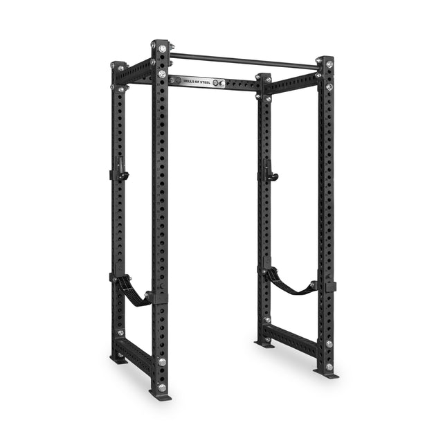 The Bells of Steel Manticore Four Post Power Rack Builder (3" x 3", 1" Holes) is a black steel squat rack featuring multiple adjustment holes, an integrated pull-up bar on top, and safety straps inside—perfectly designed for weightlifting and strength training in your home gym.